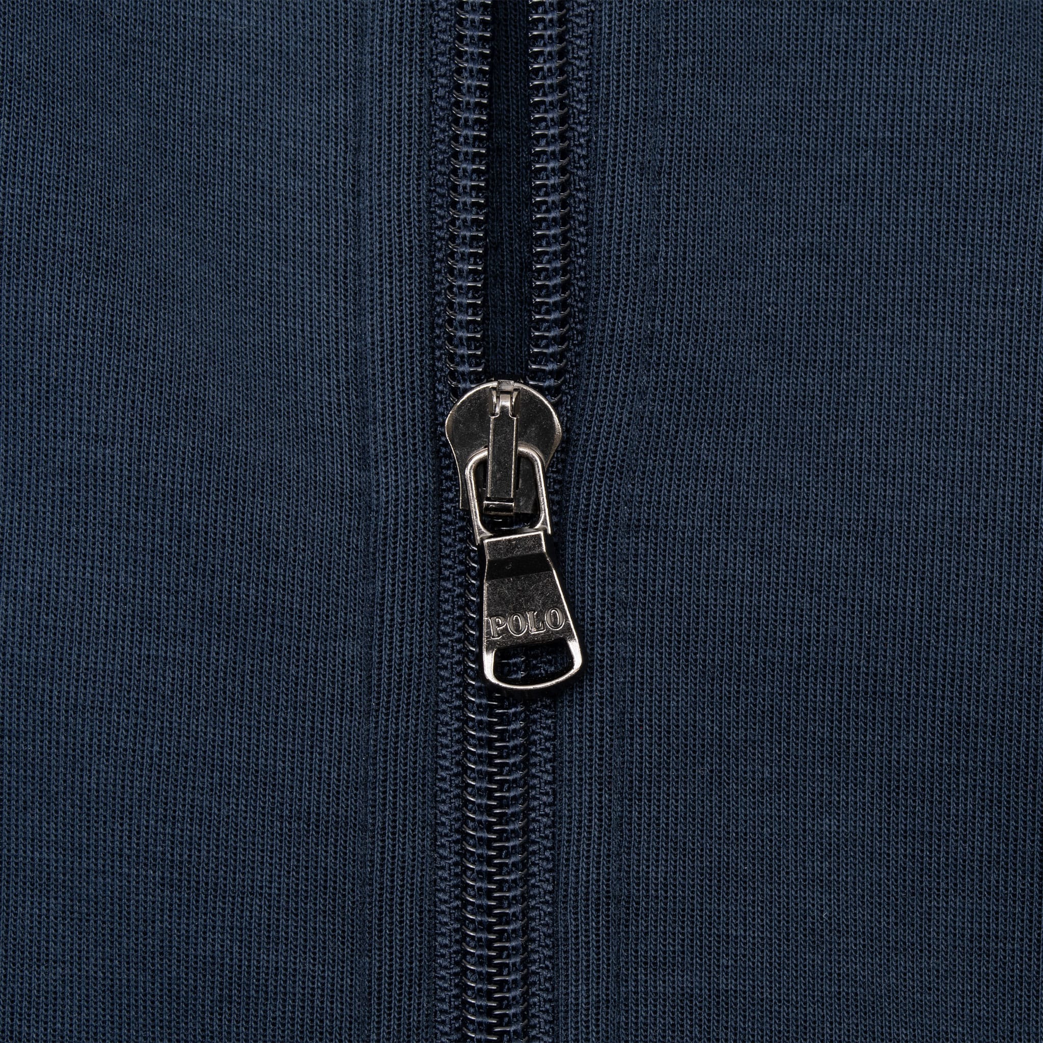 Close-up of Polo branded metal zipper pull on navy sweatshirt fabric