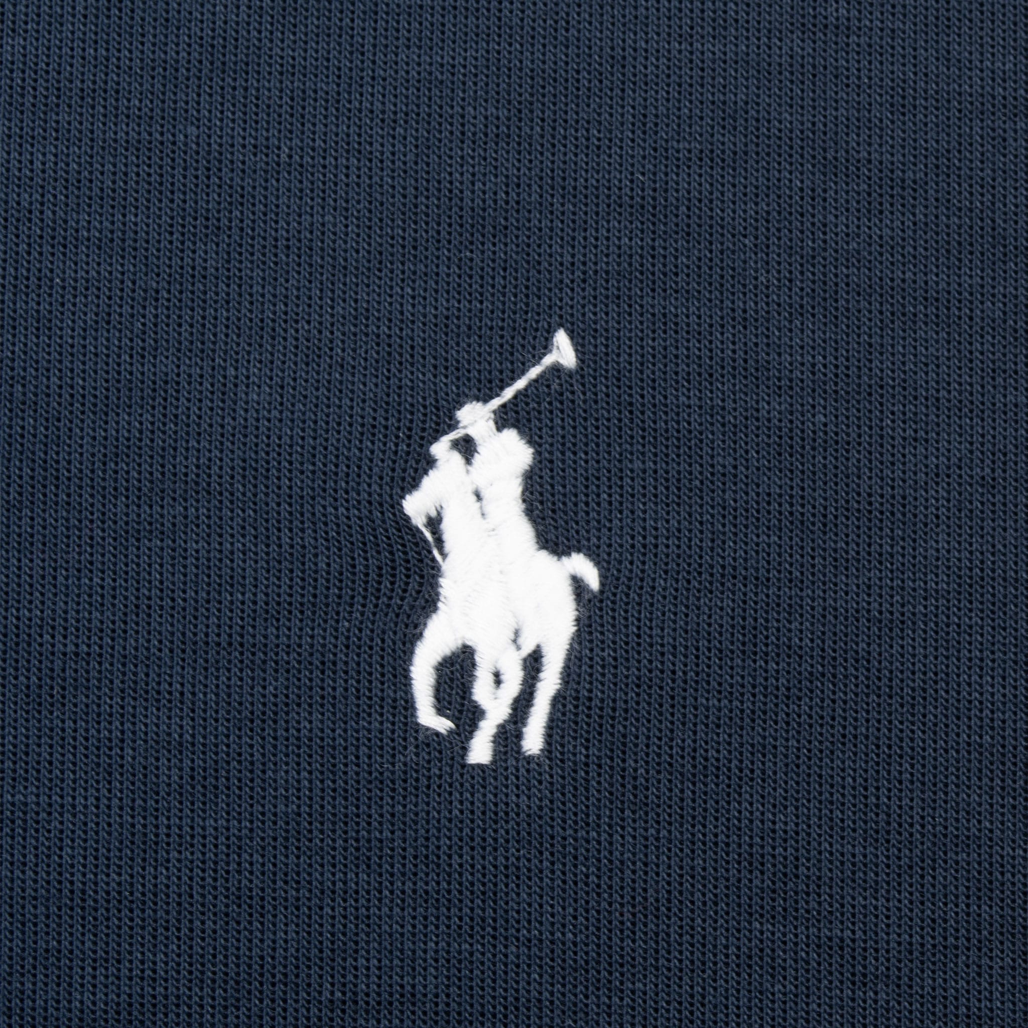 Close-up of white Polo Pony embroidery on navy sweatshirt fabric