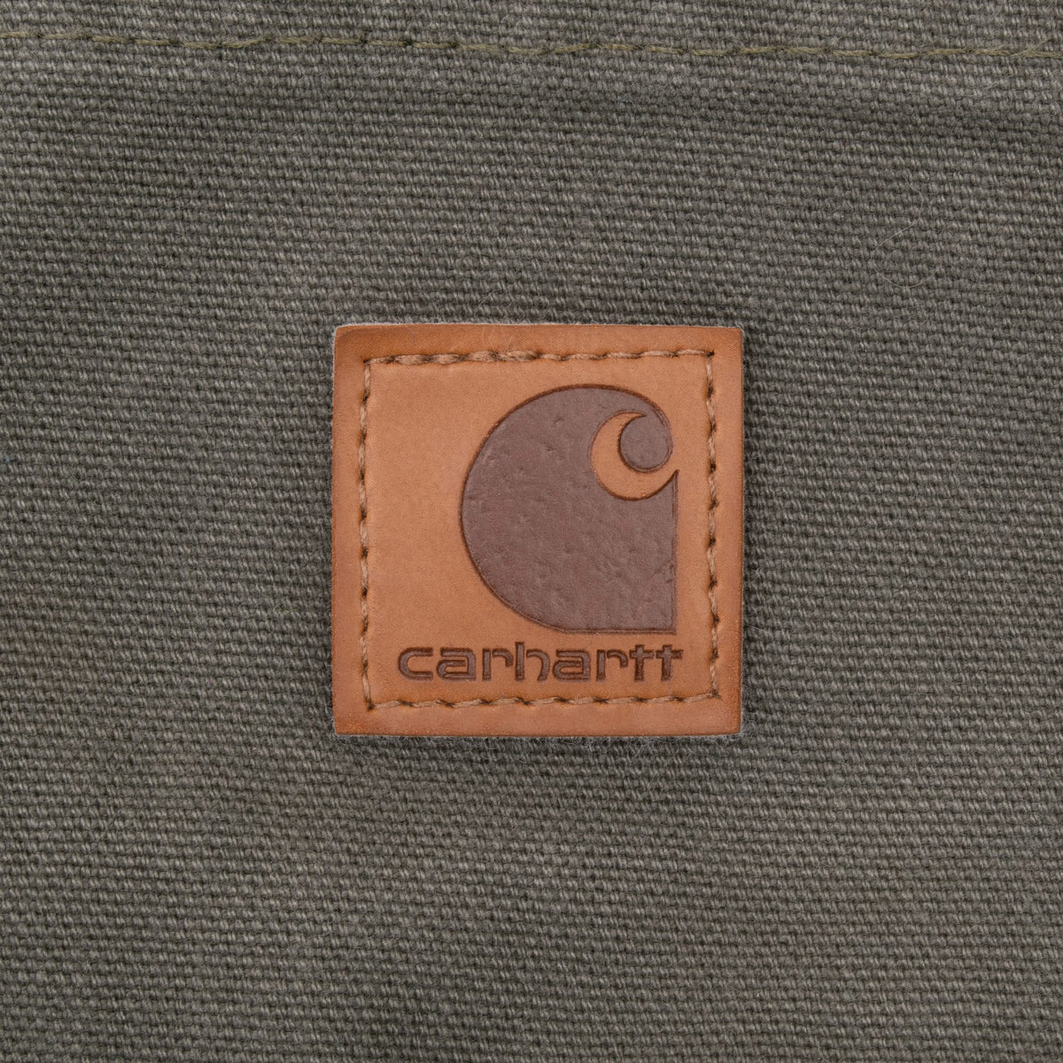 Close-up of Carhartt logo patch on green carpenter pants