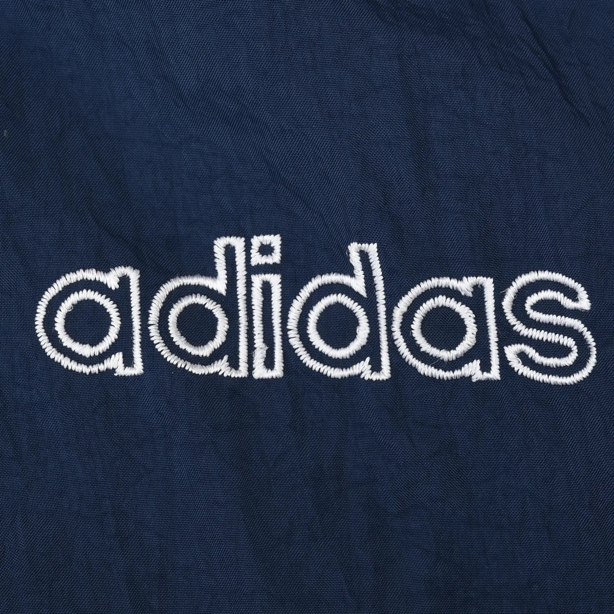 Close-up of white Adidas wordmark embroidery on navy fabric
