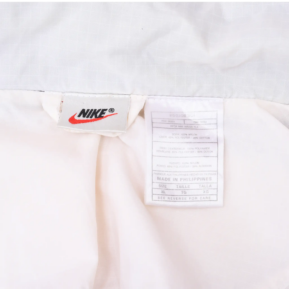 Interior Nike brand and care labels inside the white windbreaker lining