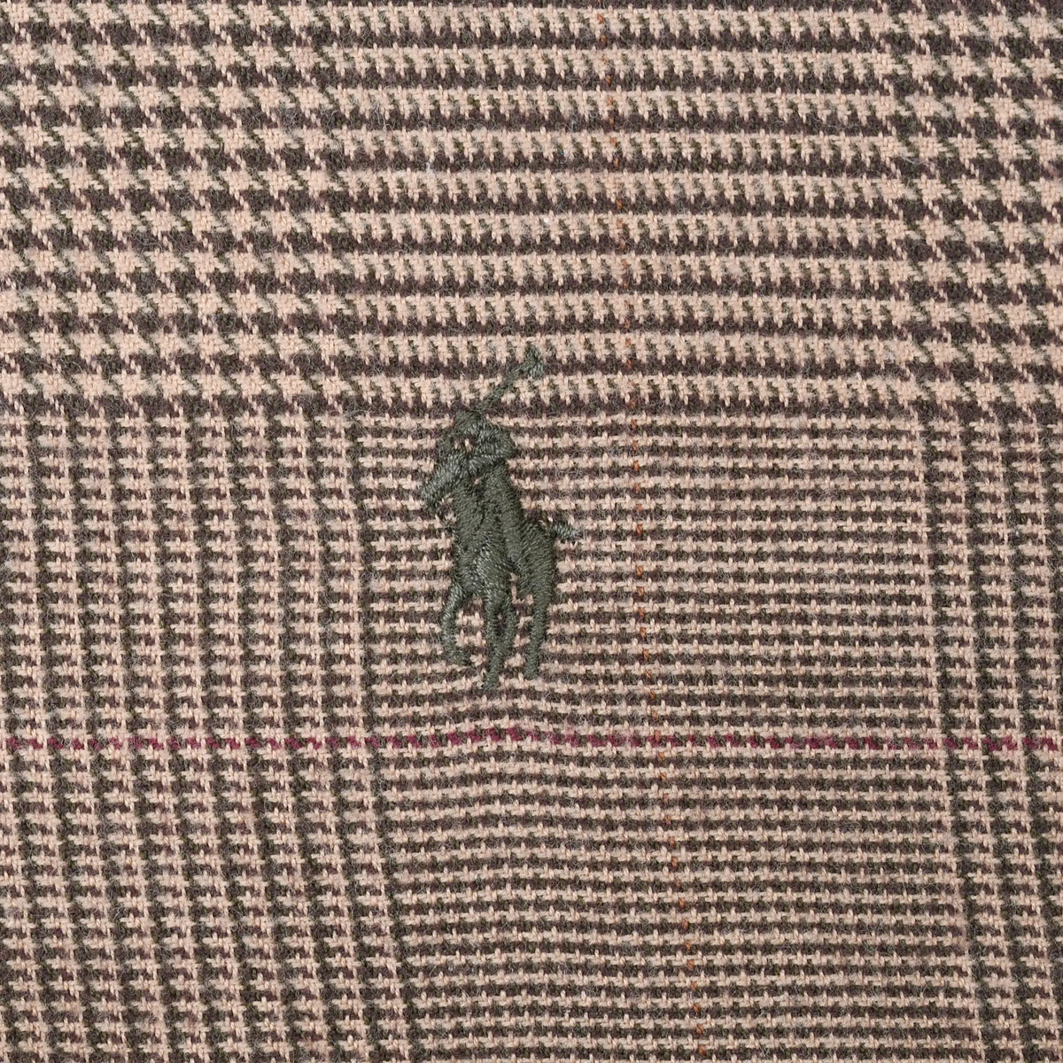Close-up of dark green Polo pony embroidery on brown plaid shirt fabric
