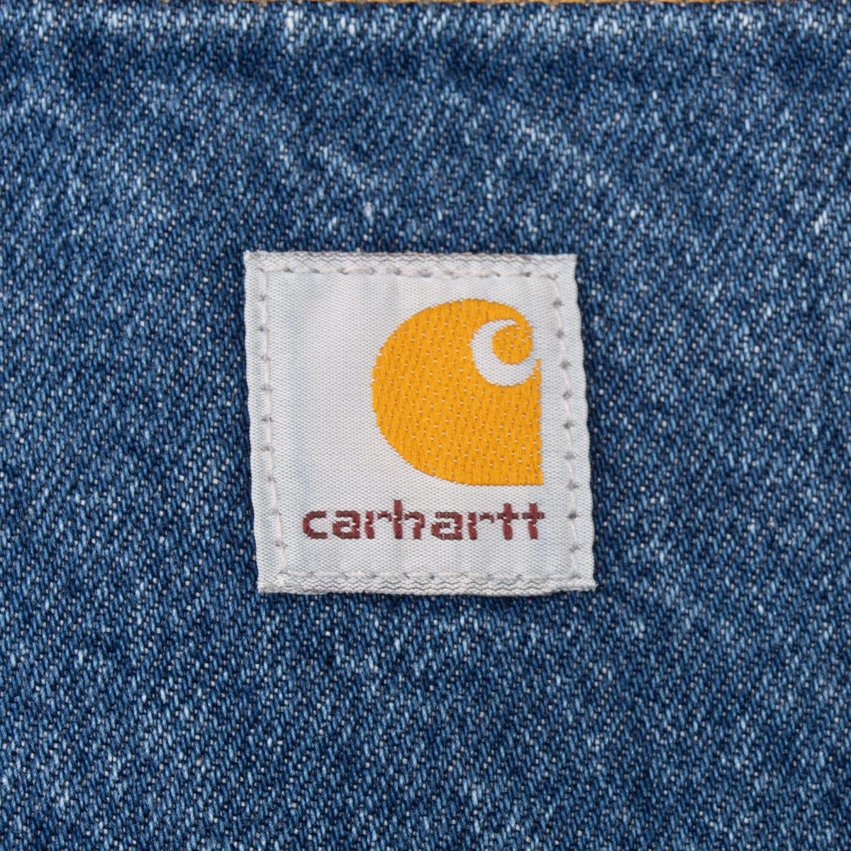 Close-up of Carhartt logo patch stitched onto blue denim