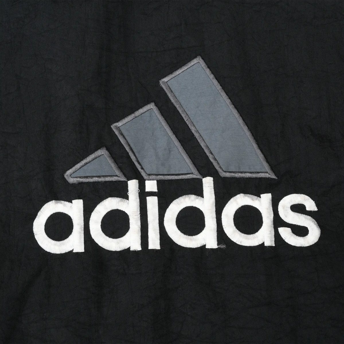 Close-up of large gray and white Adidas back logo embroidery on black fabric