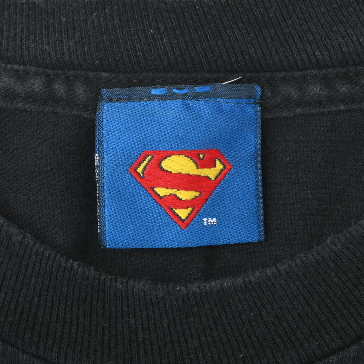 Blue neck tag with red and yellow Superman shield logo on black T-shirt