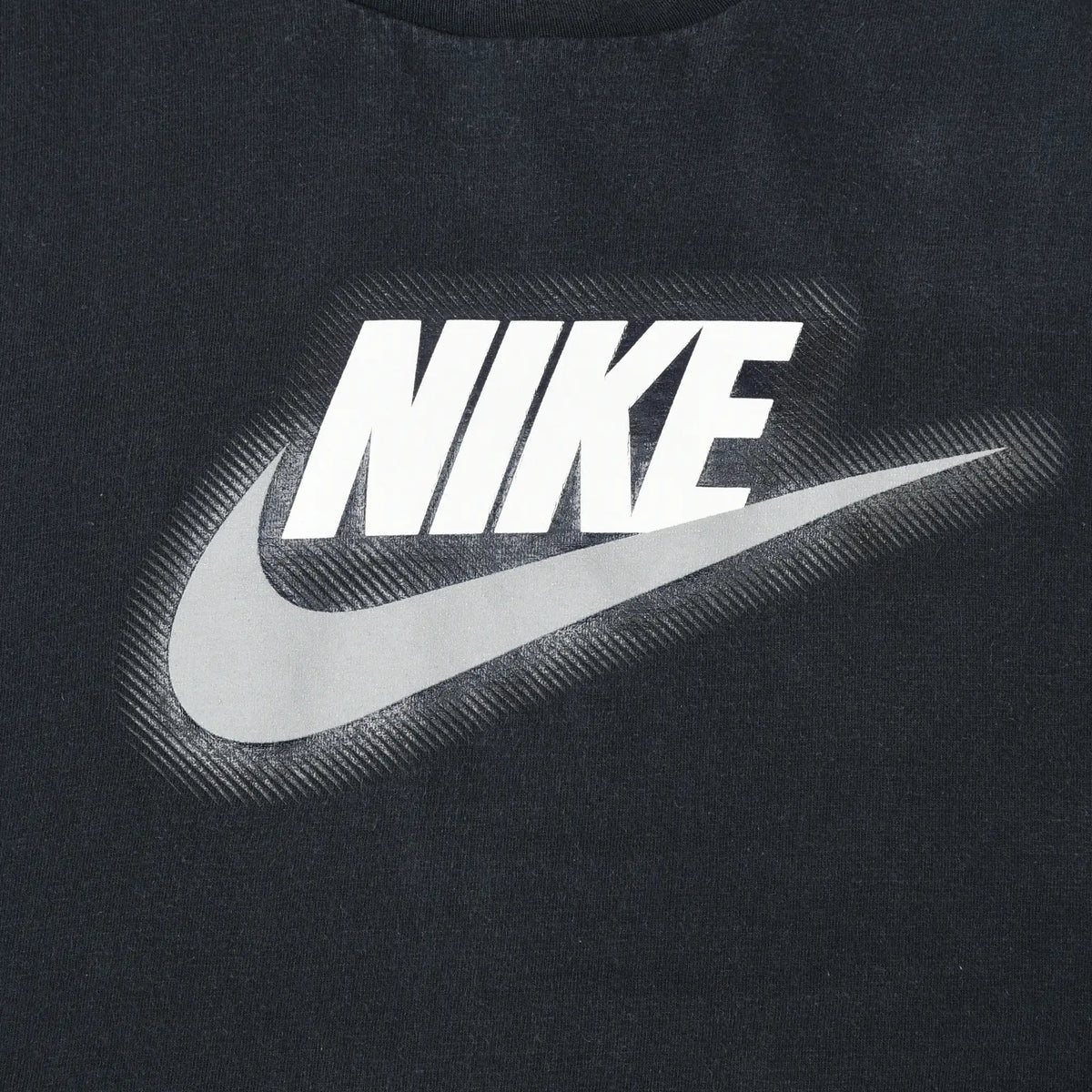 Close-up of white Nike spellout and large Swoosh print on black T-shirt