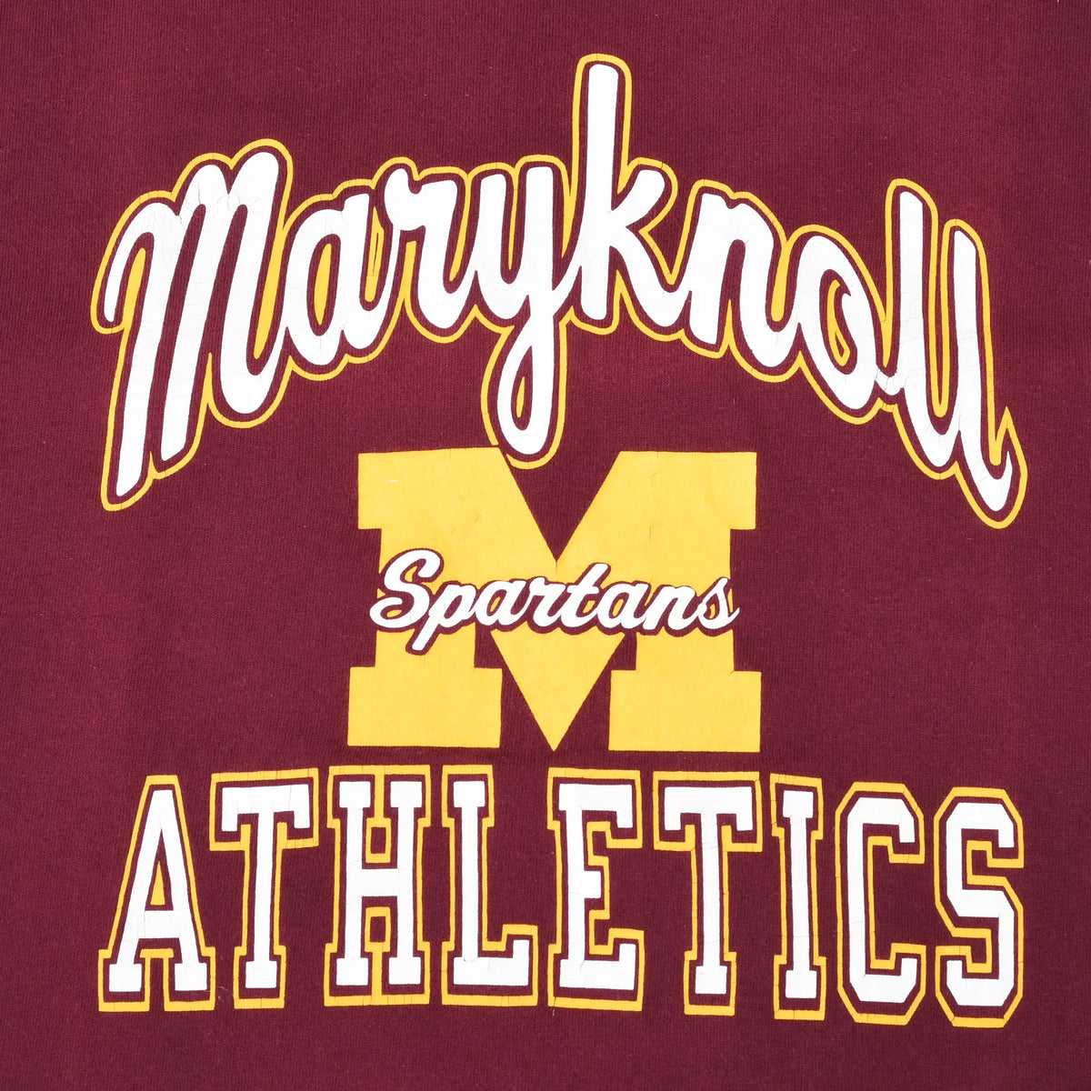 Close-up of Maryknoll Spartans Athletics graphic in white and gold