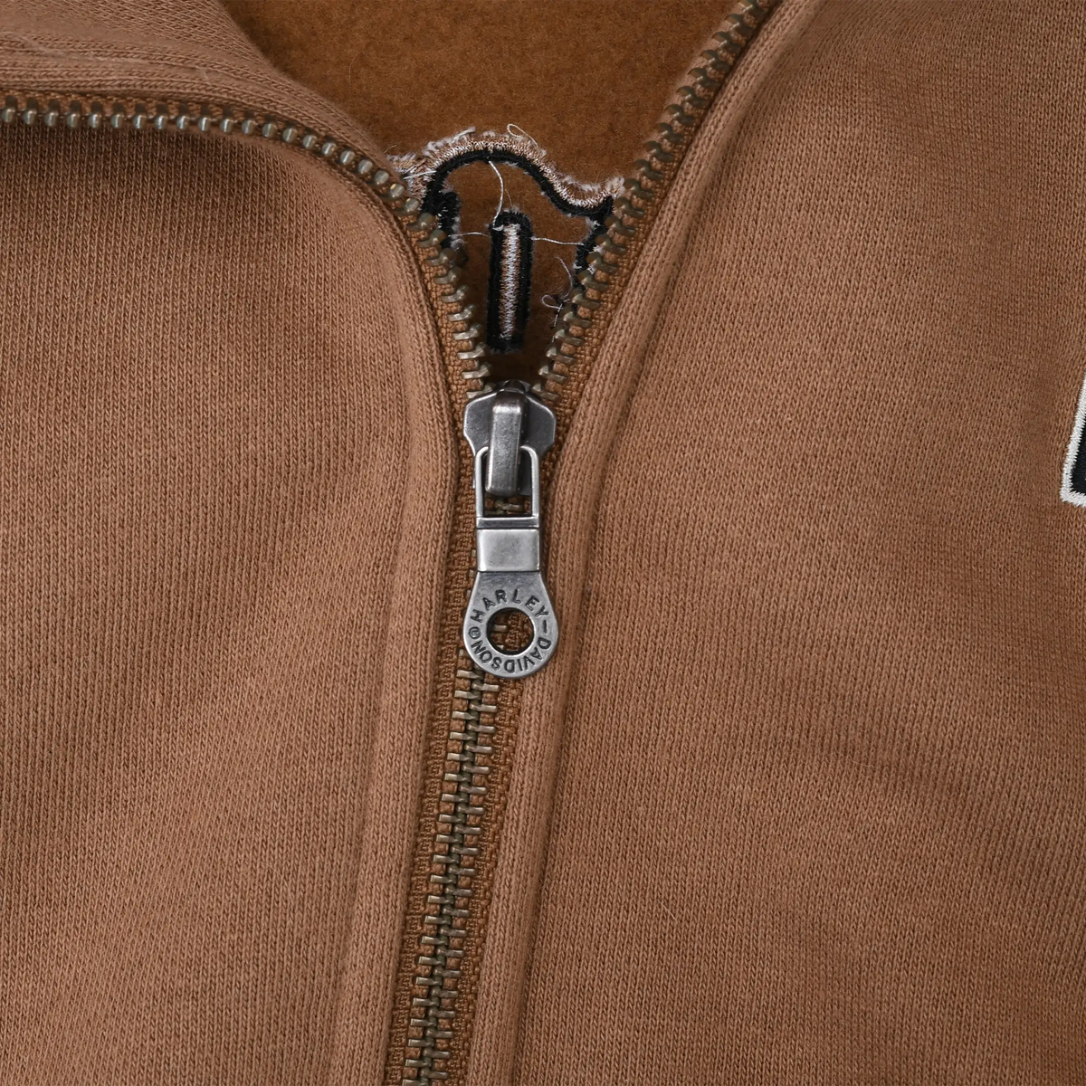 Close-up of Harley-Davidson branded metal zipper pull on brown hoodie
