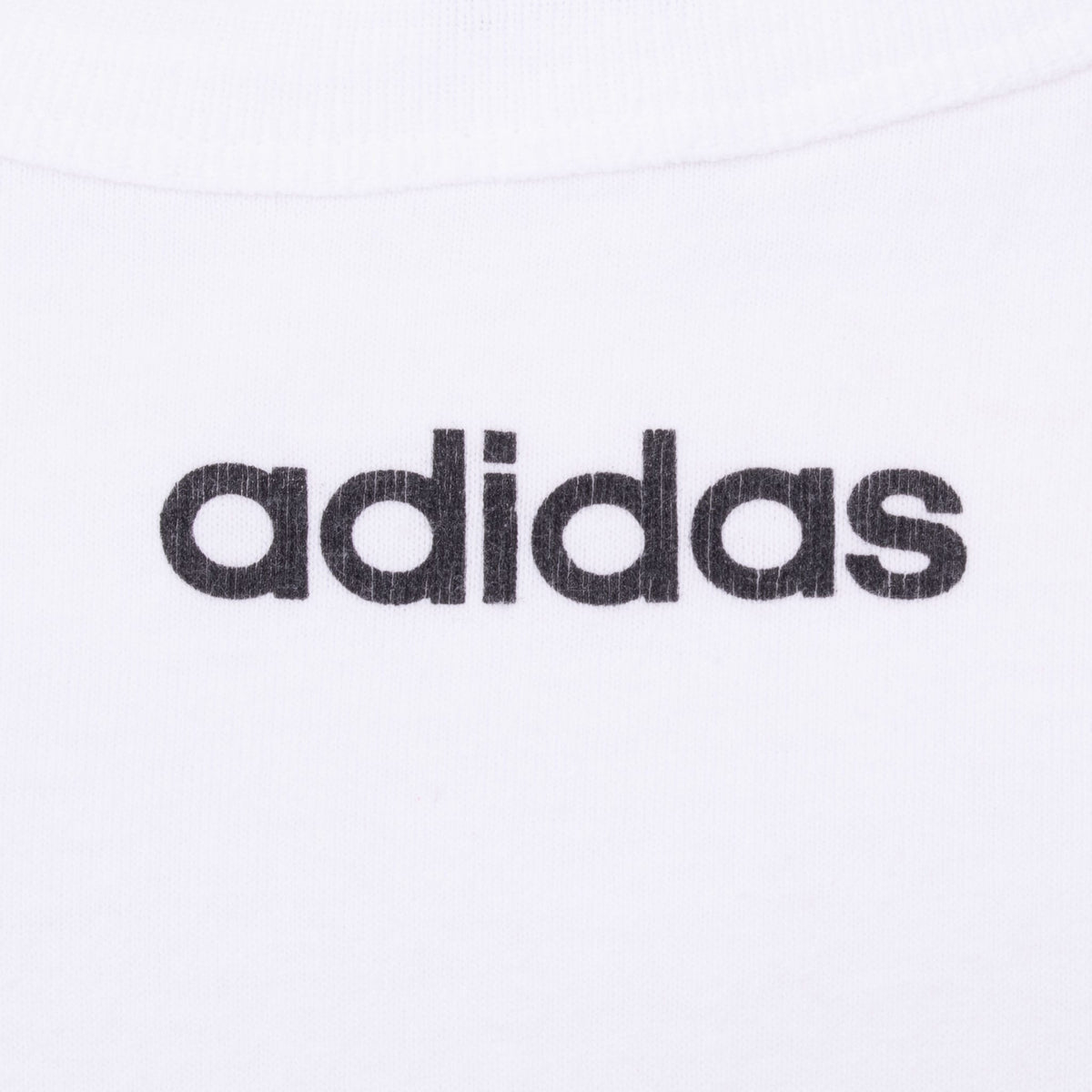 Close-up of black adidas wordmark printed below the crewneck collar