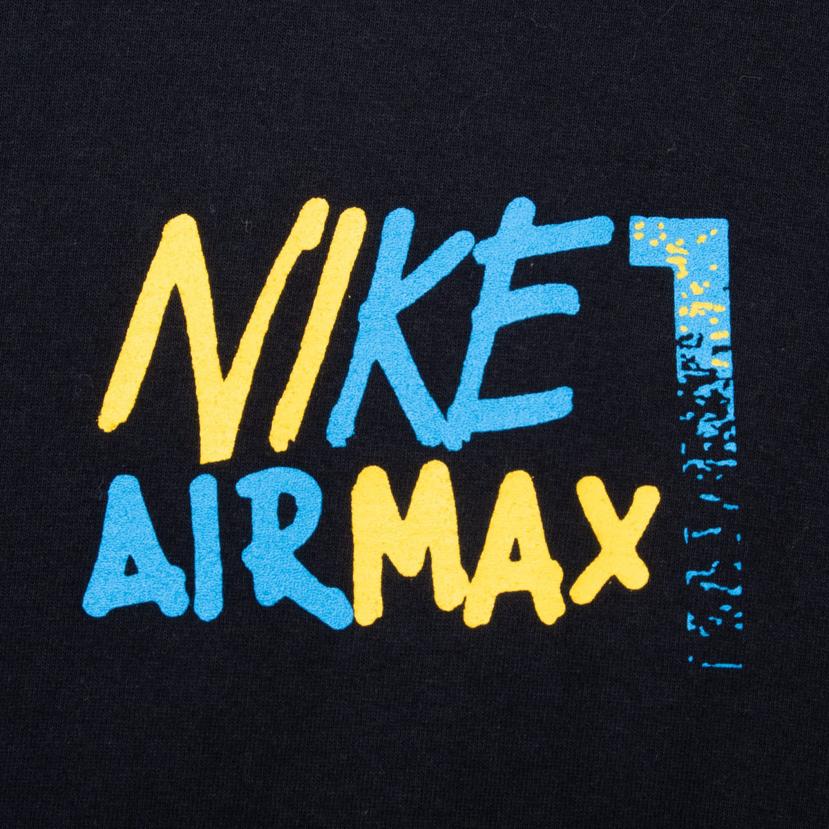 Close-up of blue and yellow Nike Air Max number 1 chest print on black fabric