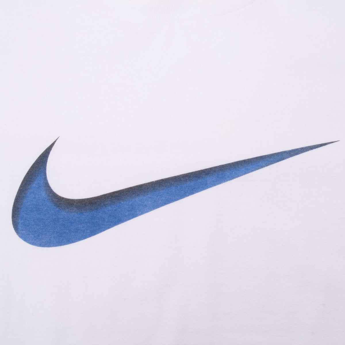 Close-up of oversized blue and black Nike Swoosh print on white T-shirt