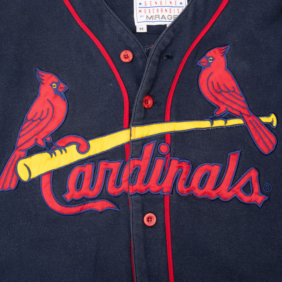 Close-up of Cardinals birds-on-bat chest logo, red buttons, and piping on navy jersey