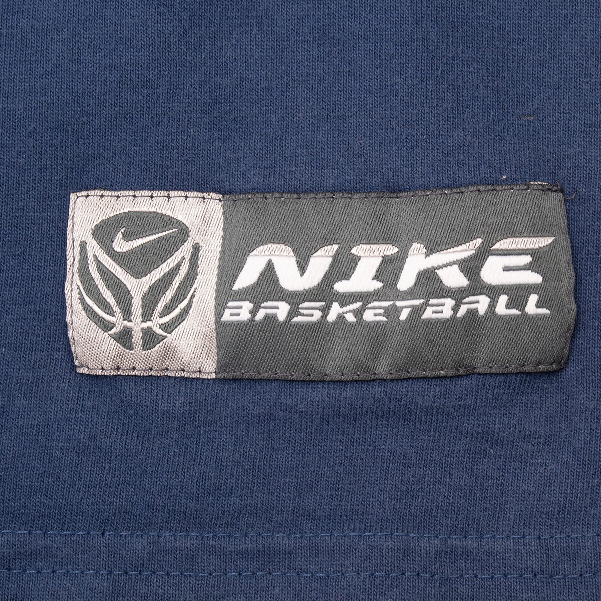 Close-up of woven Nike Basketball logo patch on the navy front hem
