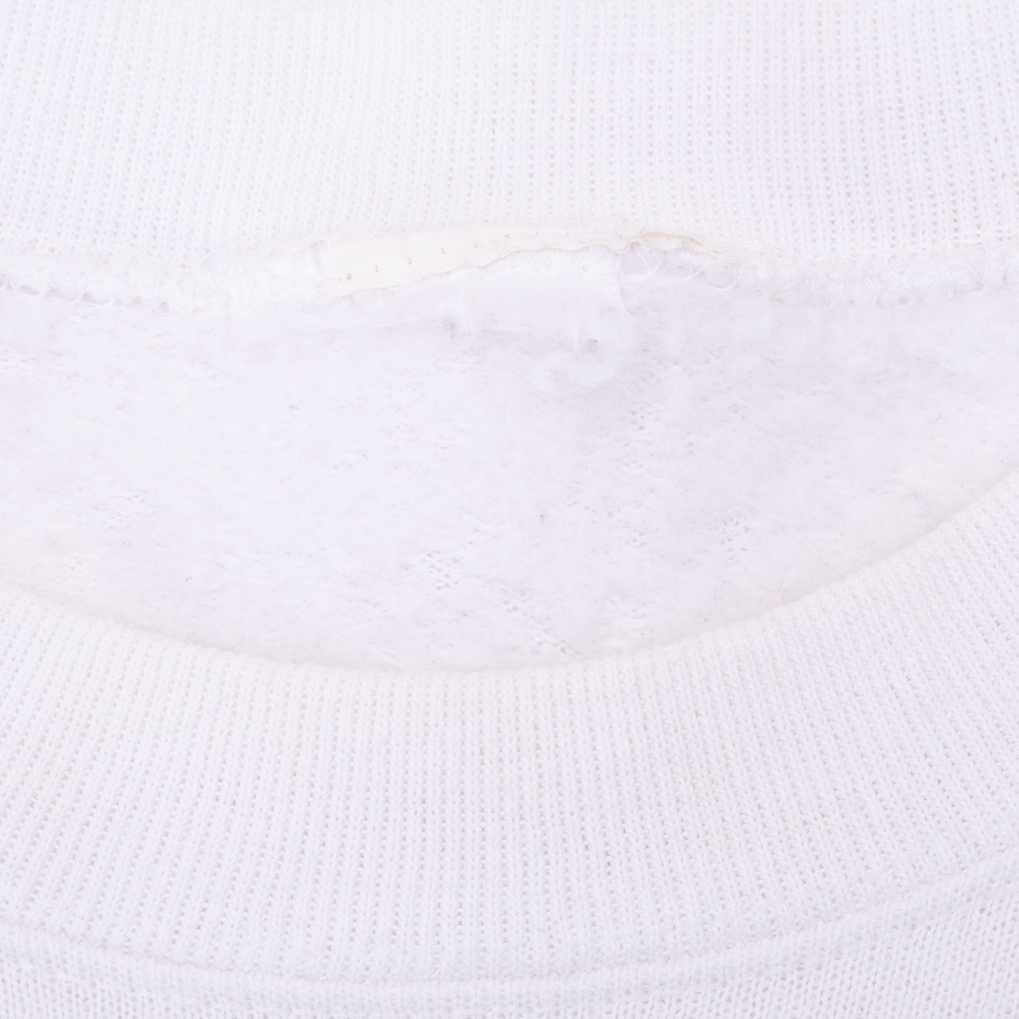 Close-up of white ribbed crewneck with faded interior label area