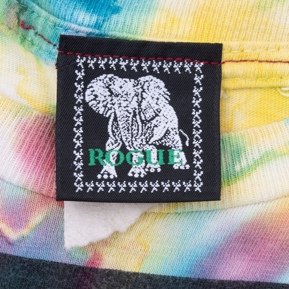 Close-up of black Rogue neck label with elephant graphic on tie-dye fabric