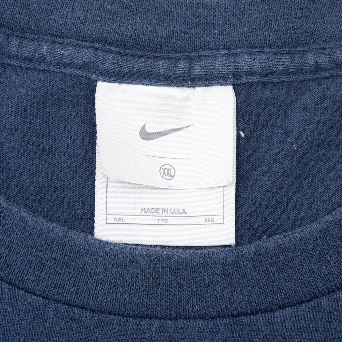 Nike neck tag showing size XXL and Made in U.S.A. on navy blue T-shirt