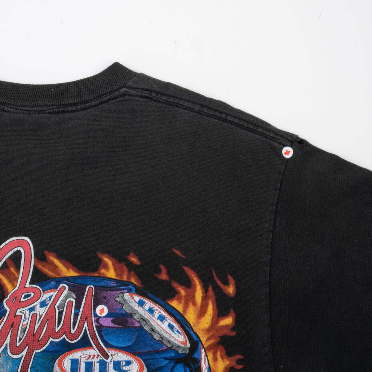 Close-up of black T-shirt upper back and shoulder seam with two small marked spots