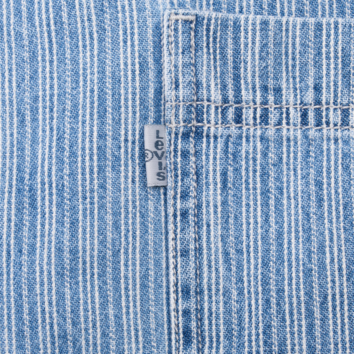 Close-up of grey Levi's tab beside the blue striped shirt pocket