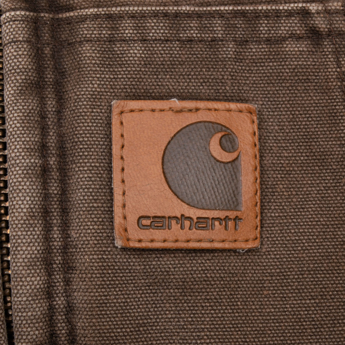 Close-up of Carhartt logo patch stitched to the brown front pouch pocket