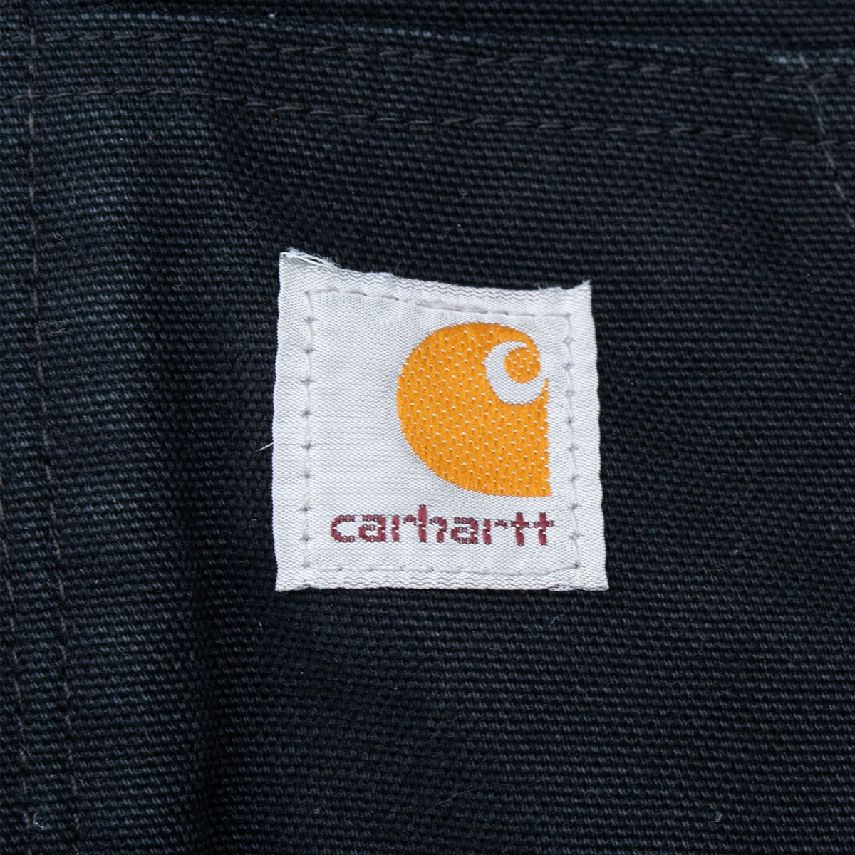 Close-up of Carhartt logo patch stitched to the black front pocket