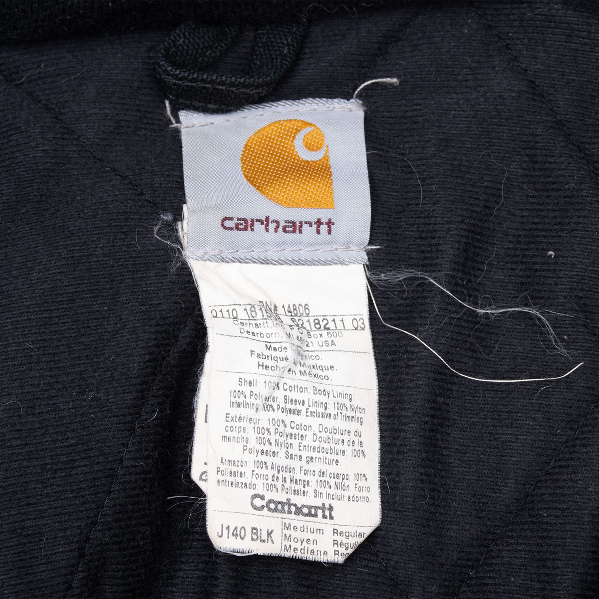 Close-up of interior Carhartt tags showing J140 BLK and Medium Regular