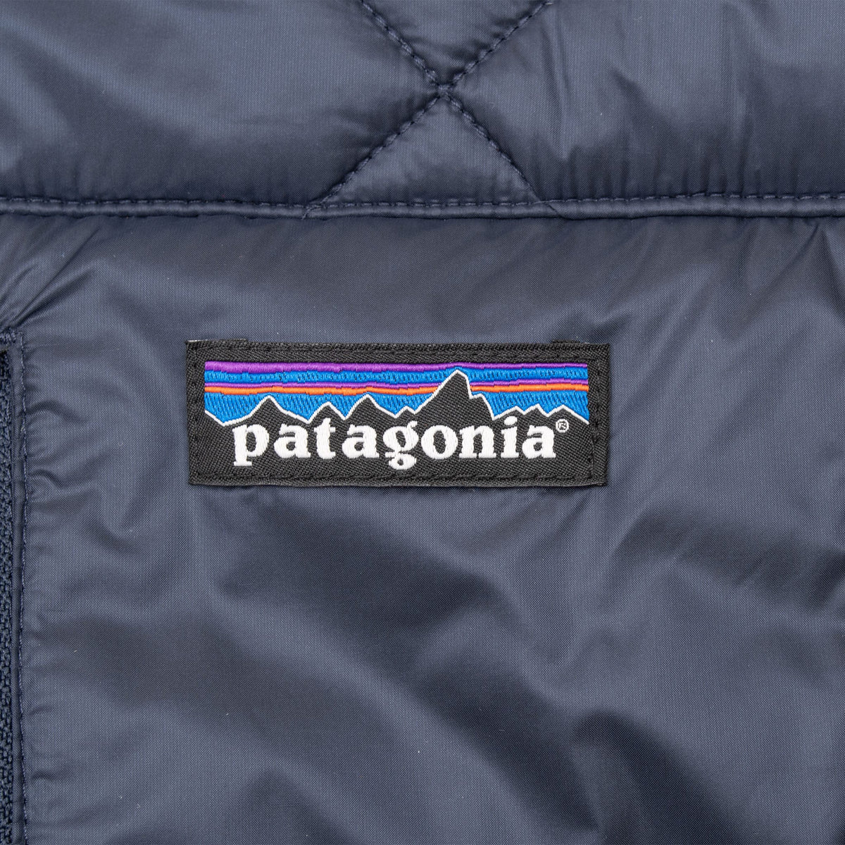 Patagonia logo patch detail on navy blue quilted parka chest pocket