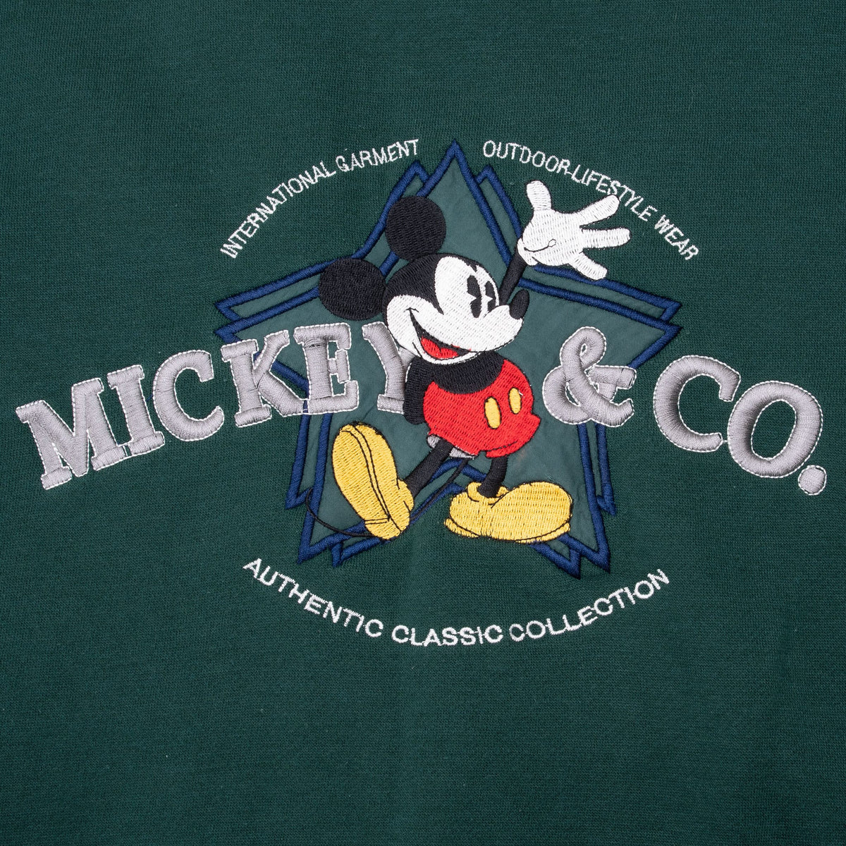 Close-up of embroidered Mickey Mouse and Mickey & Co. graphic on pine green fabric
