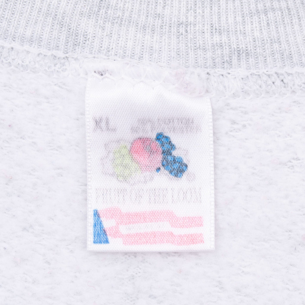 Close-up of sweatshirt neck tag marked XL with a colorful logo and American flag graphic