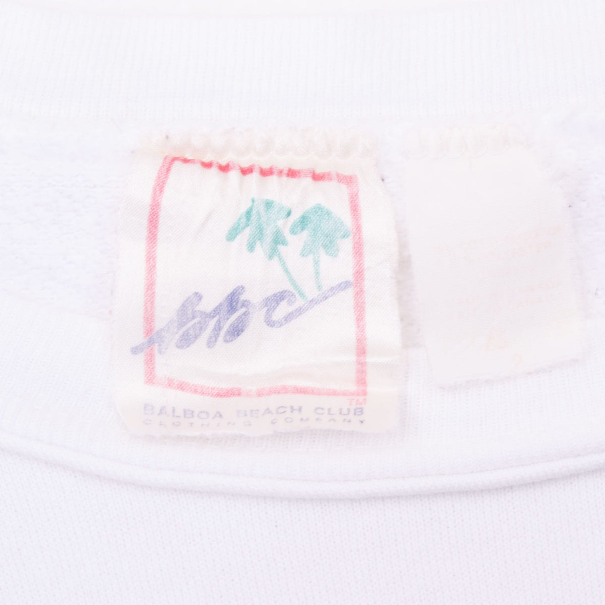 Close-up of B.J.C. Balboa Beach Club neck tag on white sweatshirt