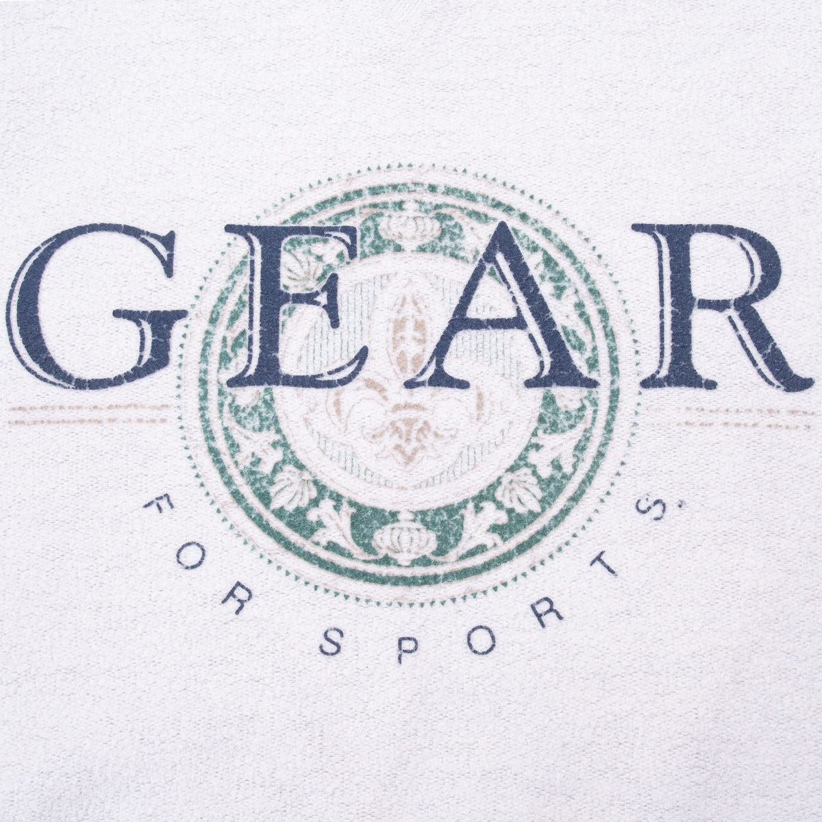 Close-up of navy GEAR for Sports print over an ornate green circular emblem