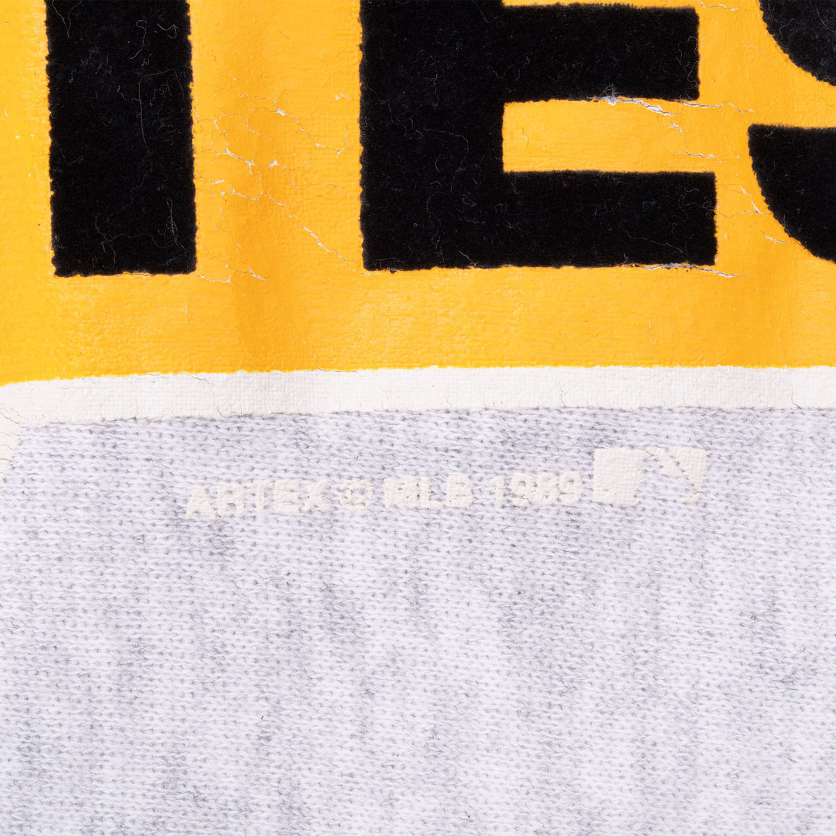 Close-up of yellow and black graphic print with visible surface cracking and faded MLB text