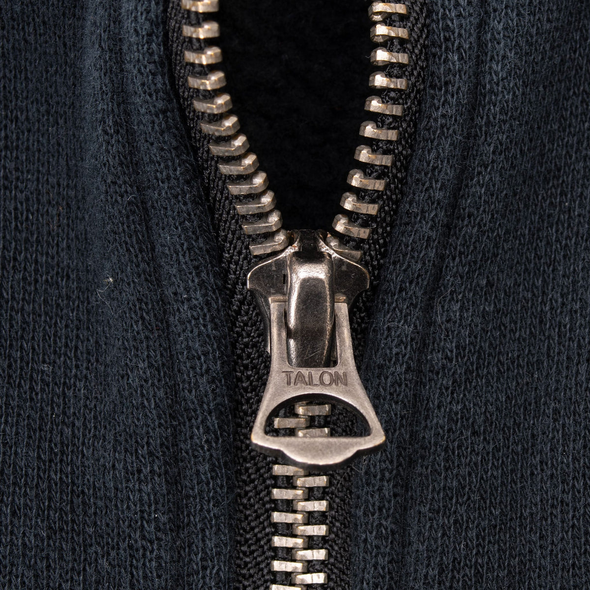 Close-up of Talon metal zipper pull on black sweatshirt