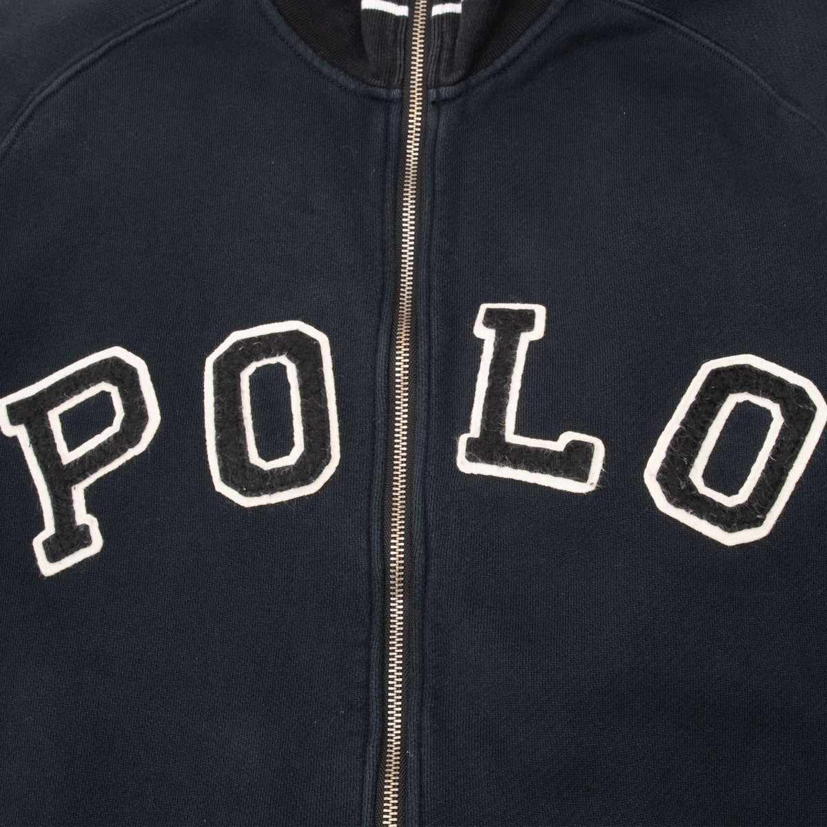 Close-up of varsity-style POLO chest lettering and metal zipper