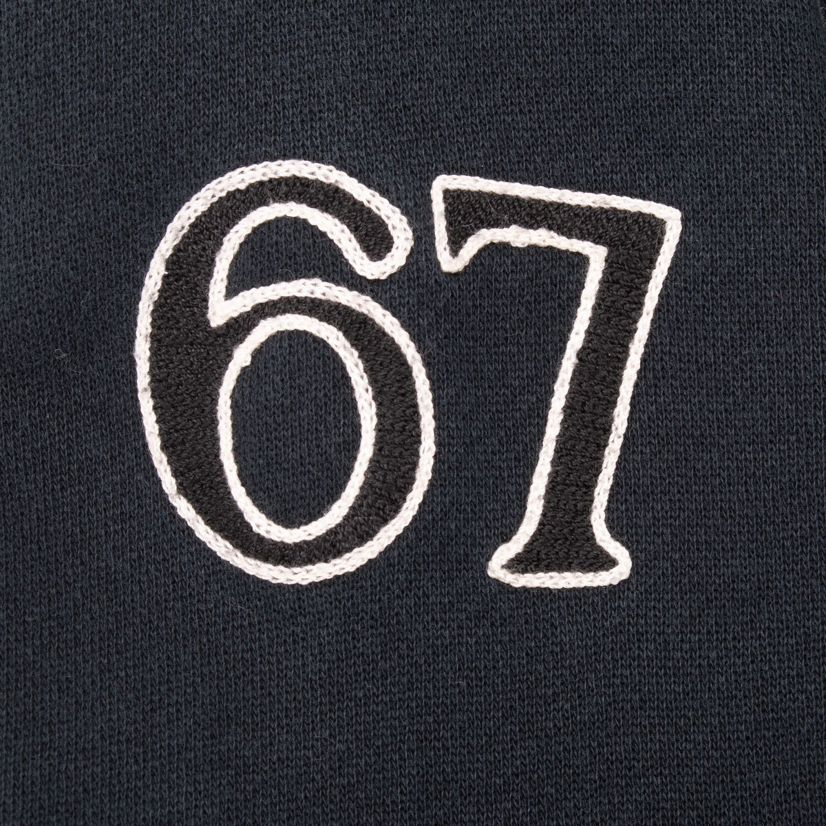 Close-up of white outlined 67 embroidery on the black sleeve
