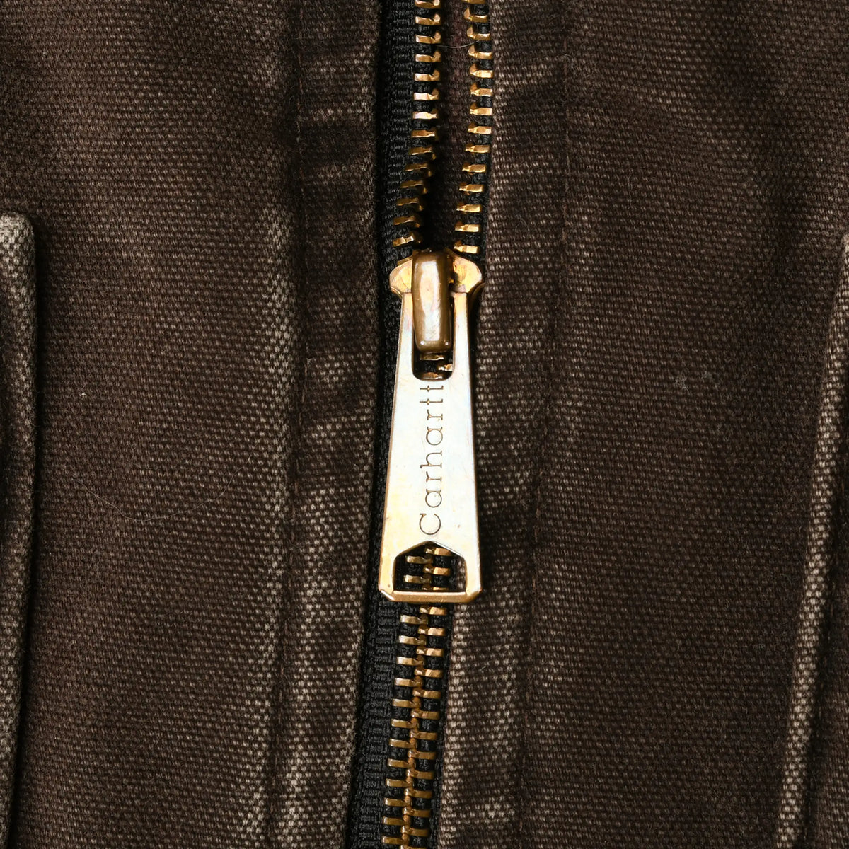 Close-up of brass-tone Carhartt zipper pull on dark brown vest