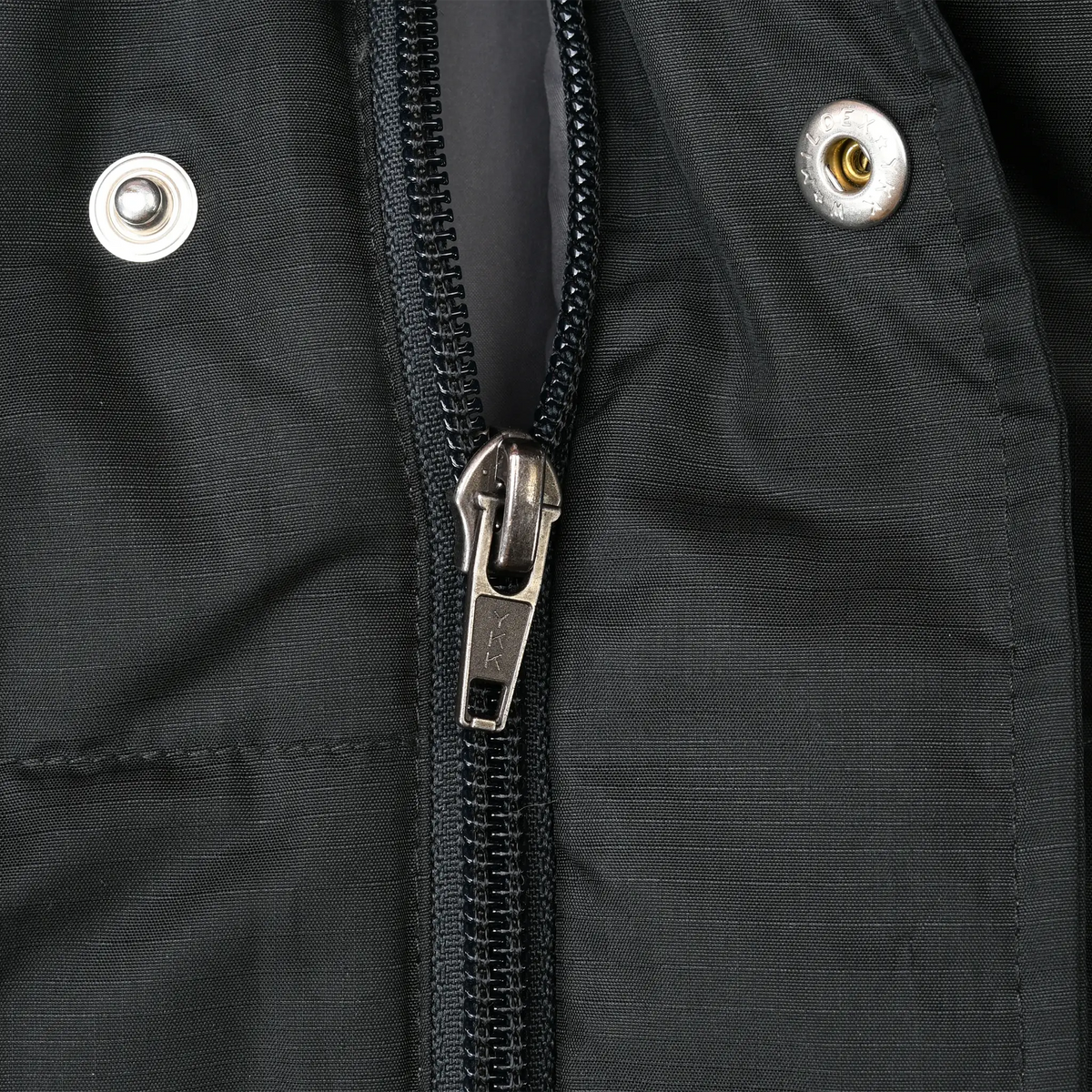 Close-up of black Patagonia vest front zipper, metal pull, and snap fasteners