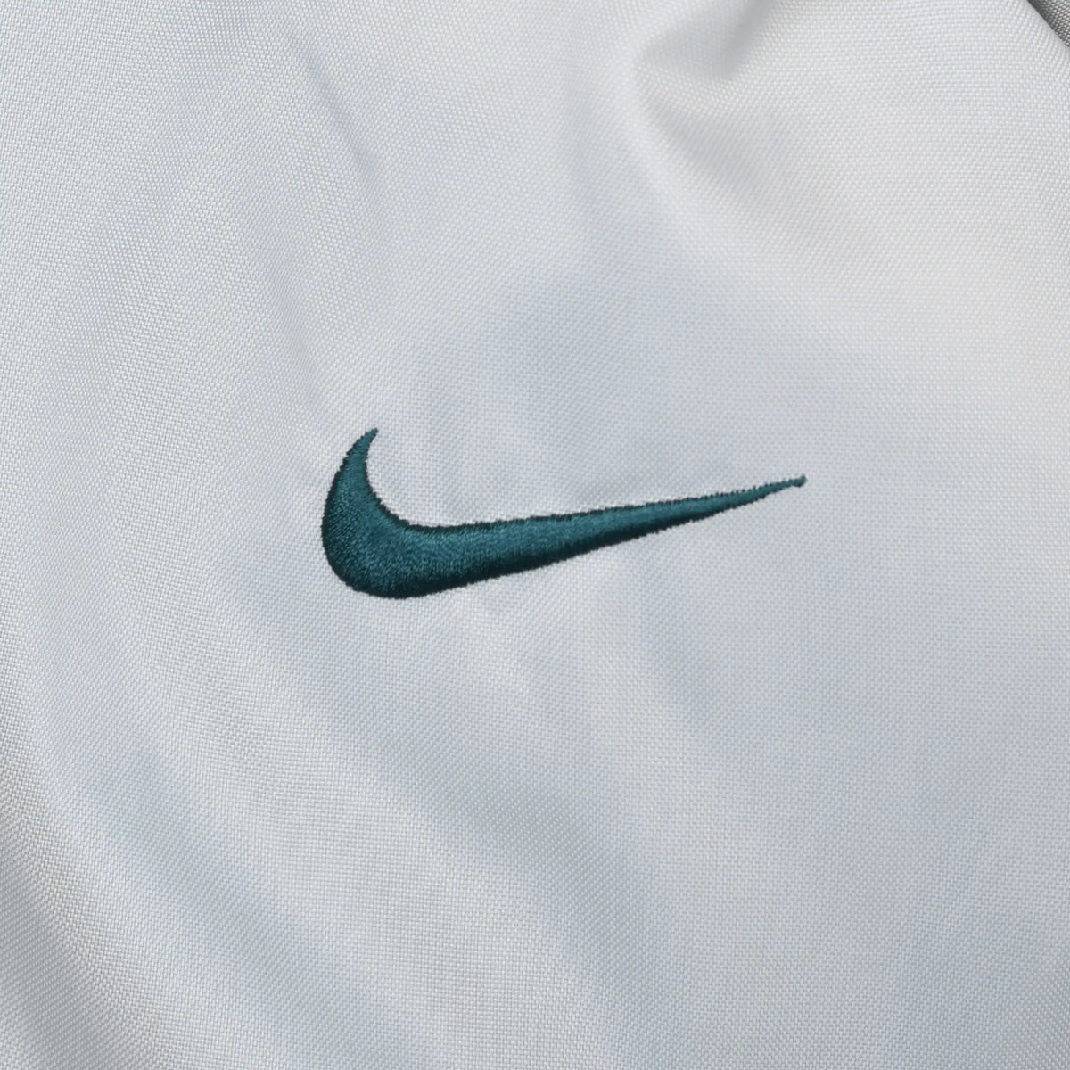 Close-up of small green Nike Swoosh embroidery on light grey fabric