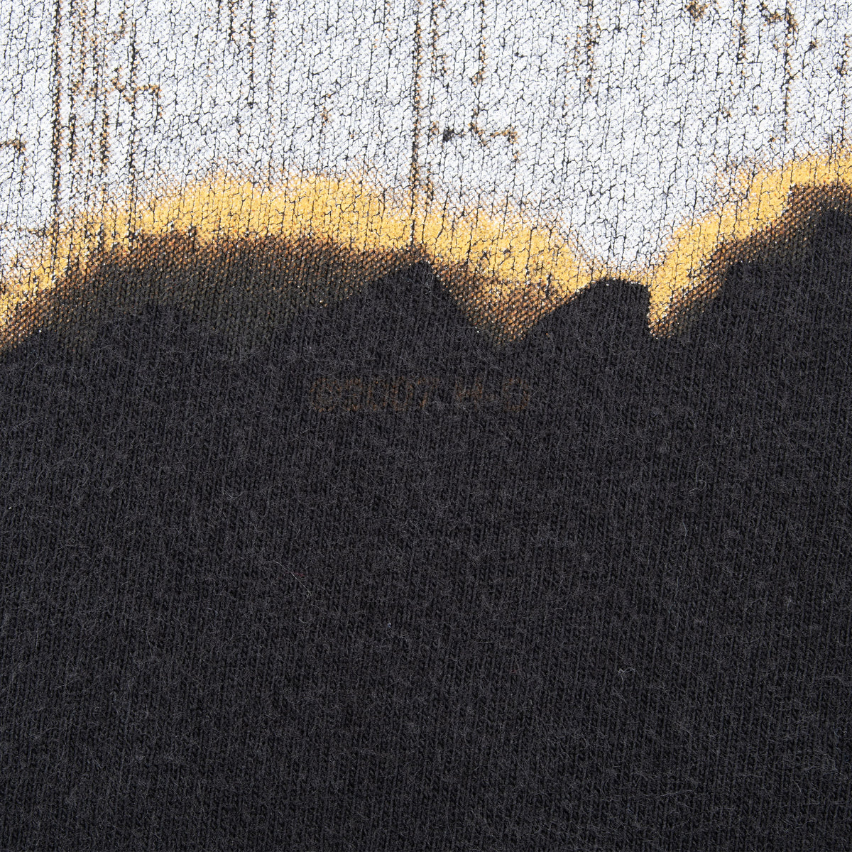 Close-up of the distressed cream and tan back print against black fabric