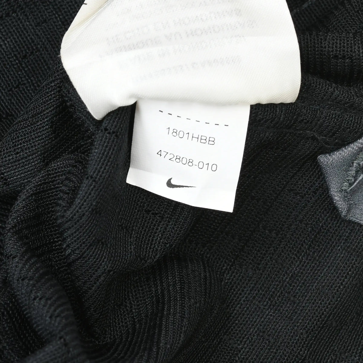 Close-up of white Nike care tag with product codes inside the black jersey