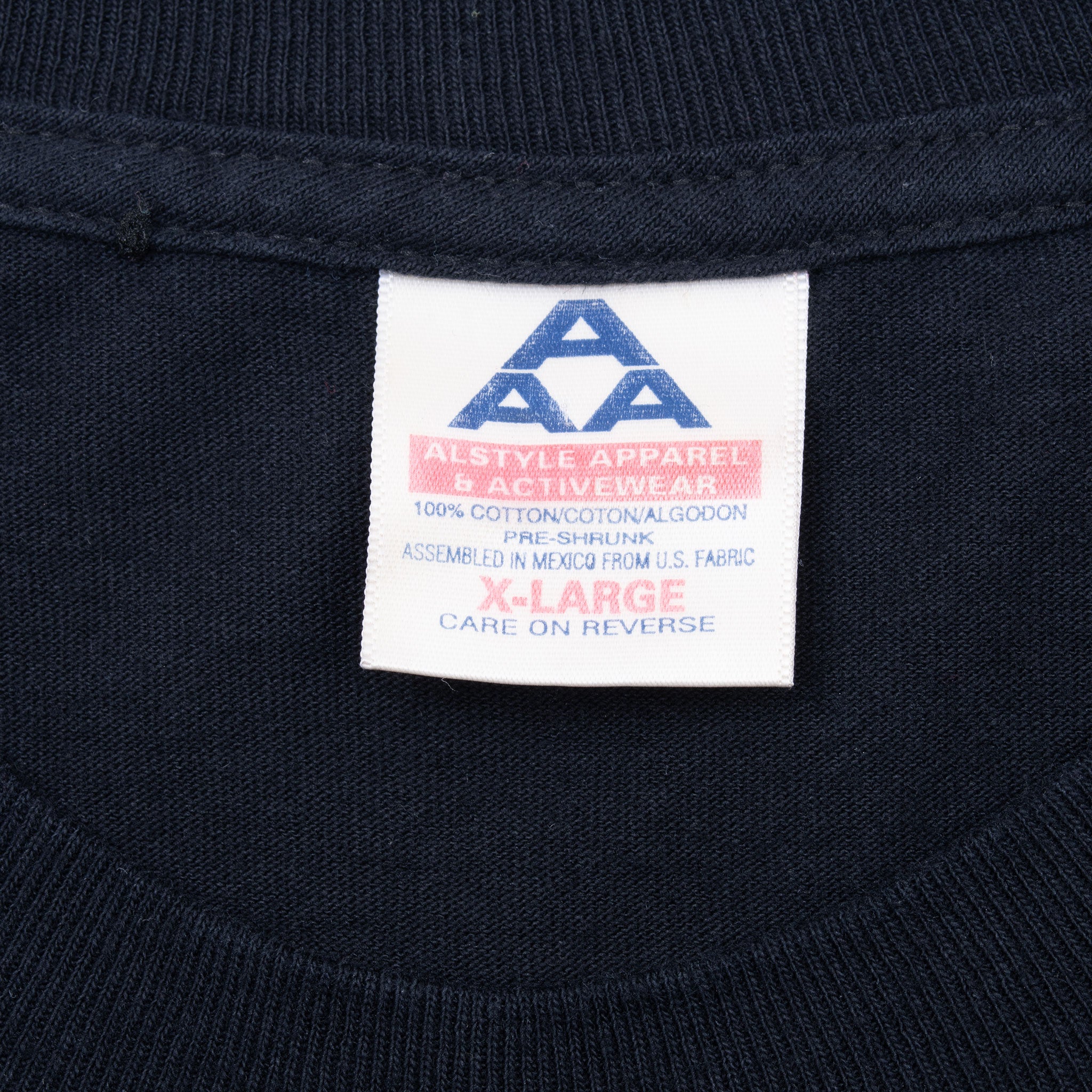 Close-up of Alstyle Apparel & Activewear XL neck tag on black T-shirt