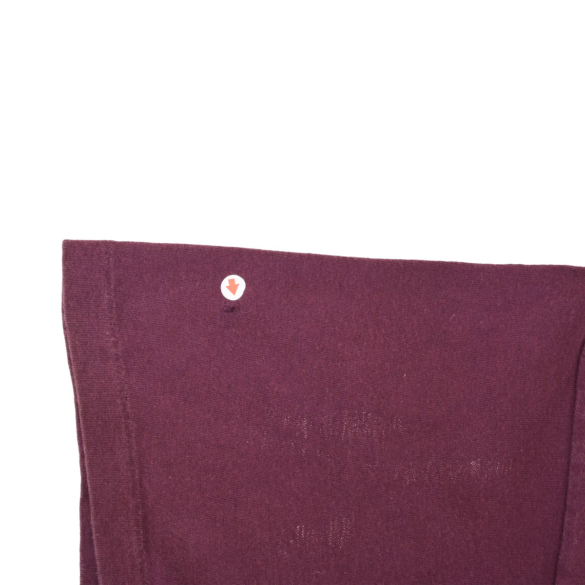 Close-up of burgundy T-shirt sleeve hem showing single-stitch construction