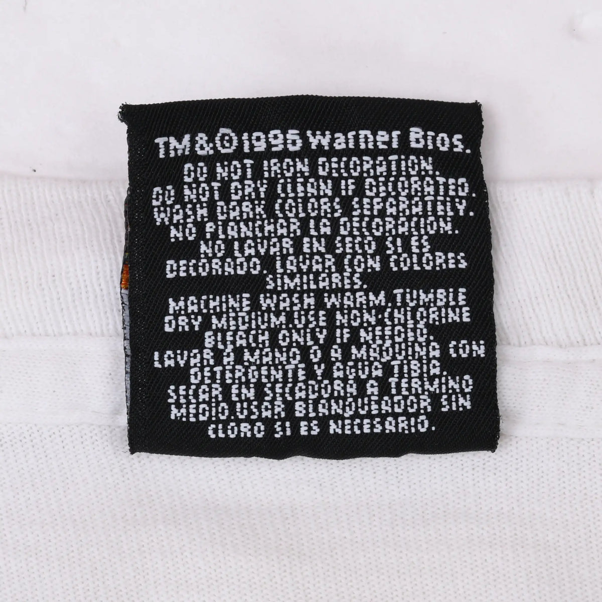 Reverse of black garment tag with Warner Bros. copyright and bilingual care instructions