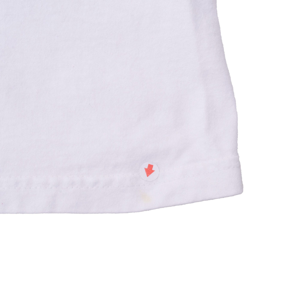 Close-up of white T-shirt hem with arrow marking a small yellow spot