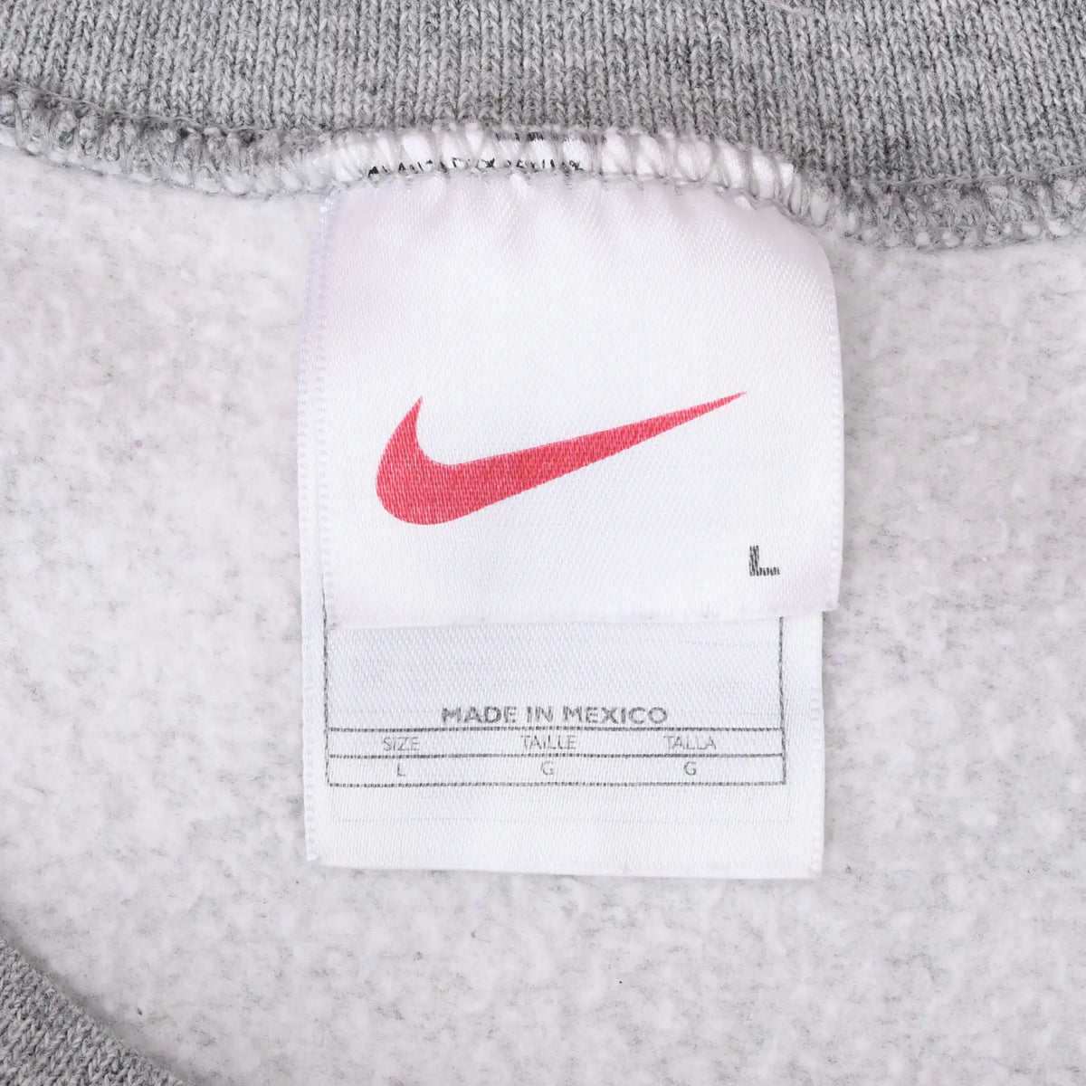 Close-up of white Nike neck tag with red Swoosh inside gray sweatshirt
