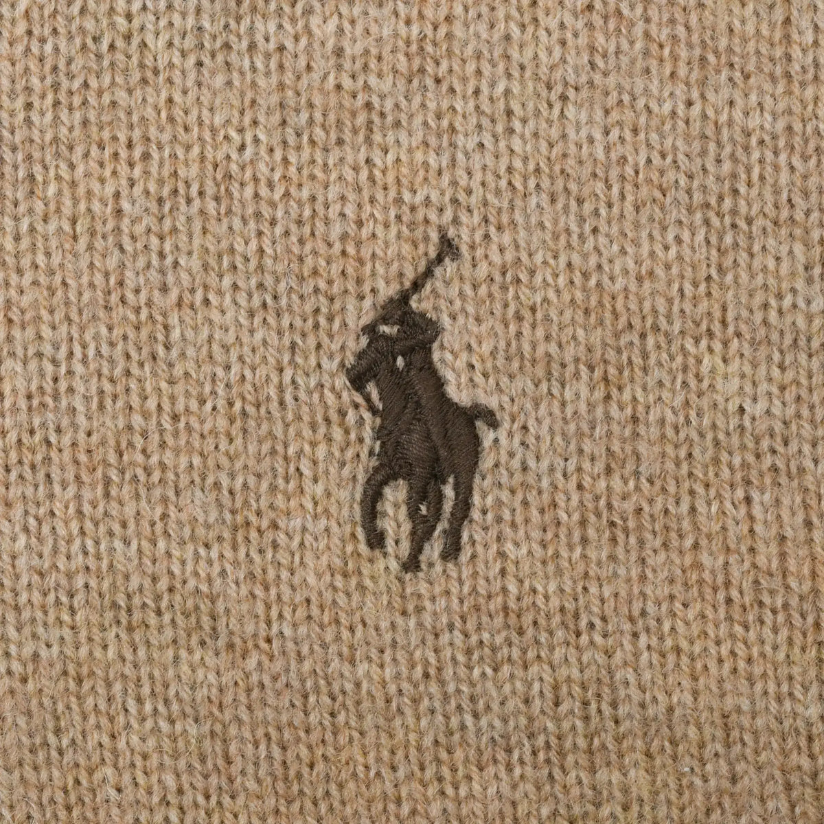 Close-up of dark brown Polo pony embroidery on beige knit fabric