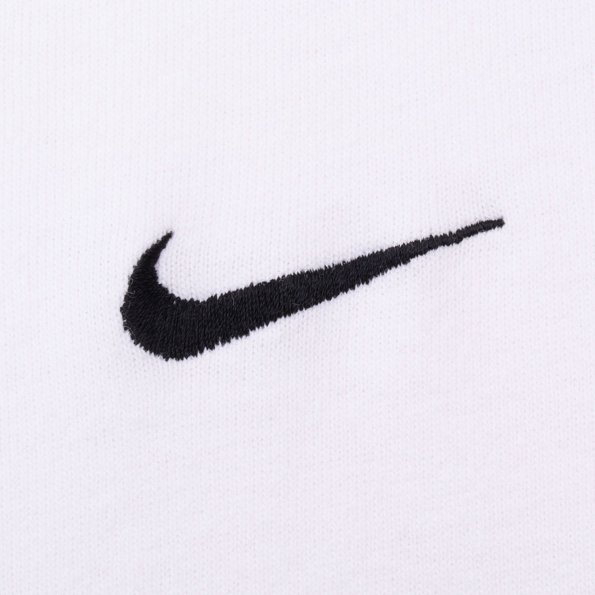 Close-up of black embroidered Nike Swoosh on white fabric
