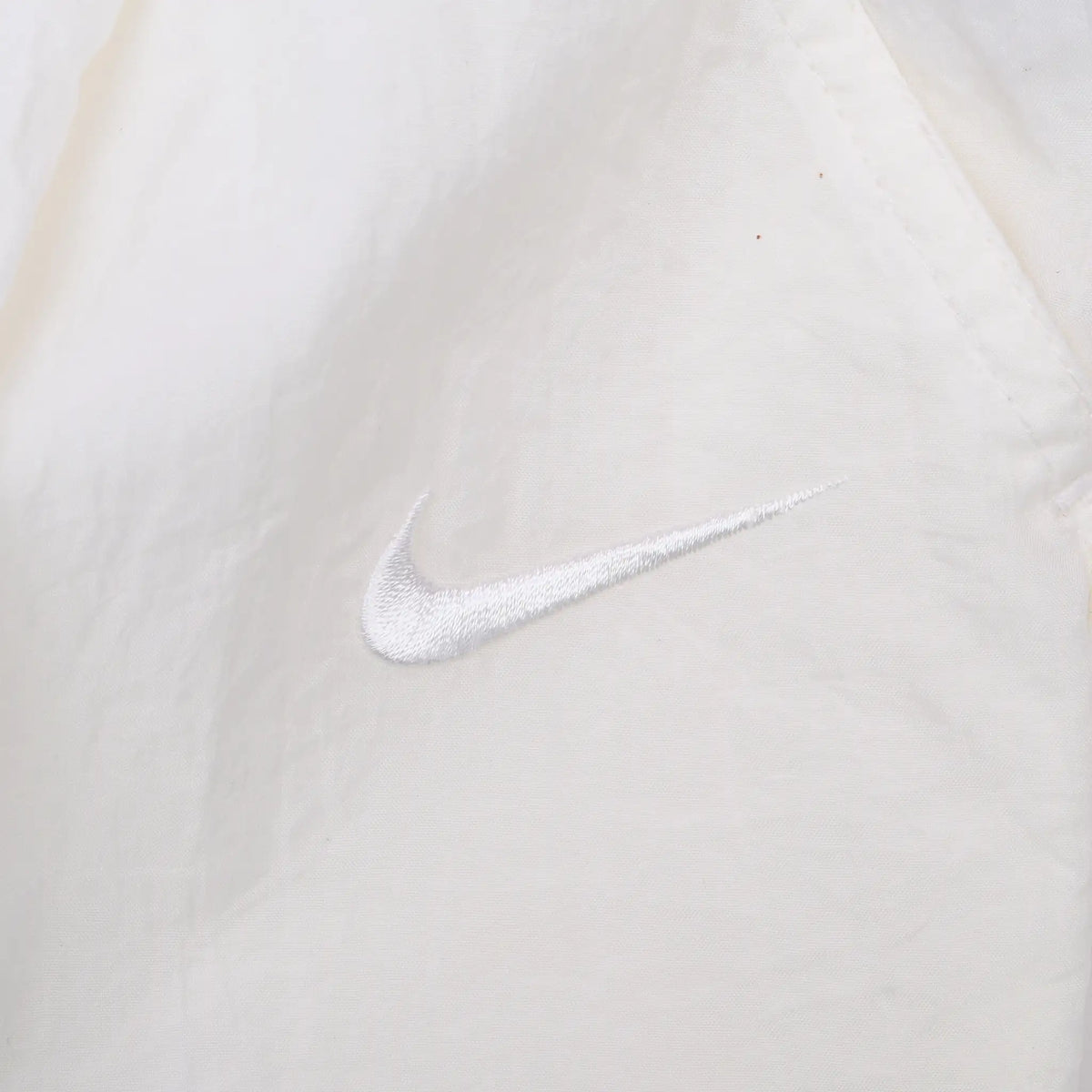 Close-up of tonal white Nike Swoosh embroidery on white fabric