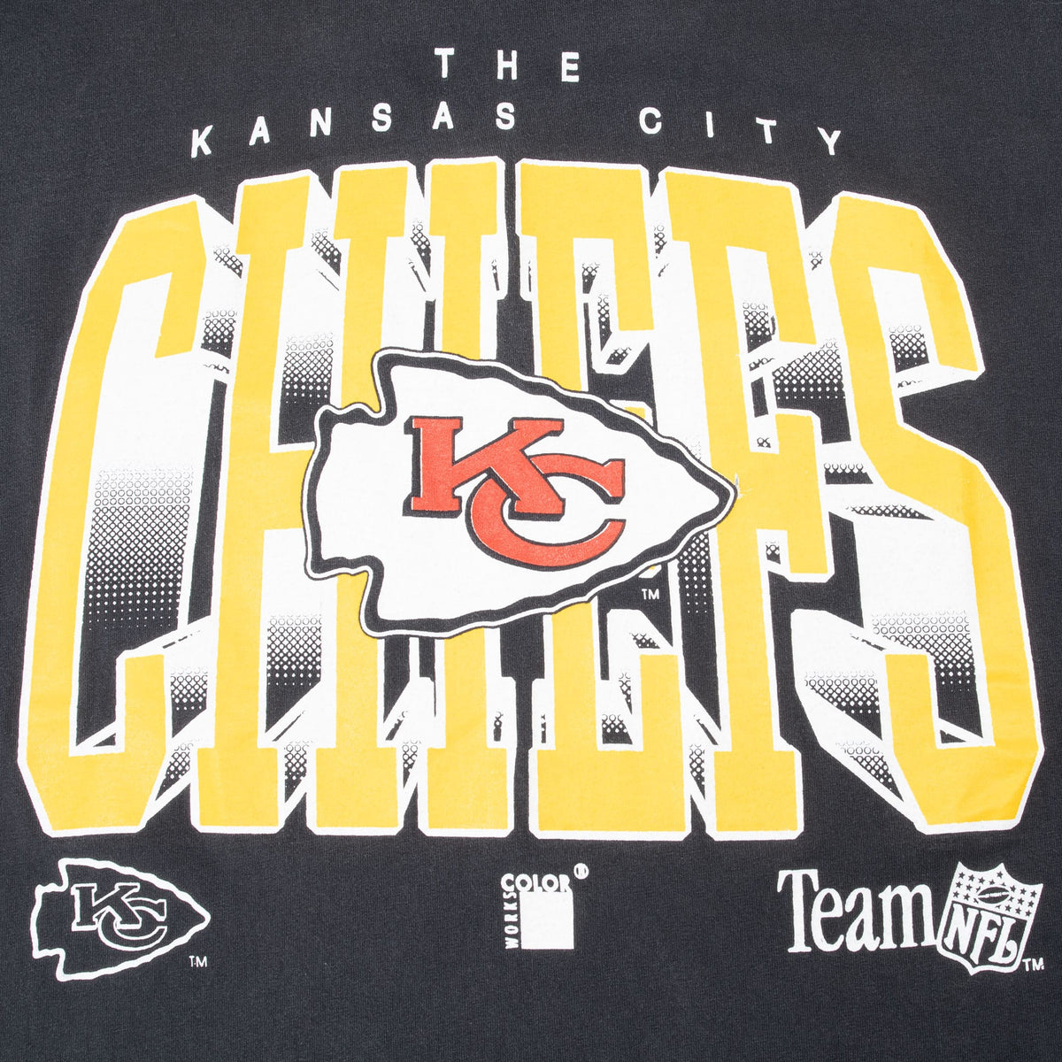 Close-up of yellow Chiefs print, red KC arrowhead logo, and Team NFL mark on black T-shirt