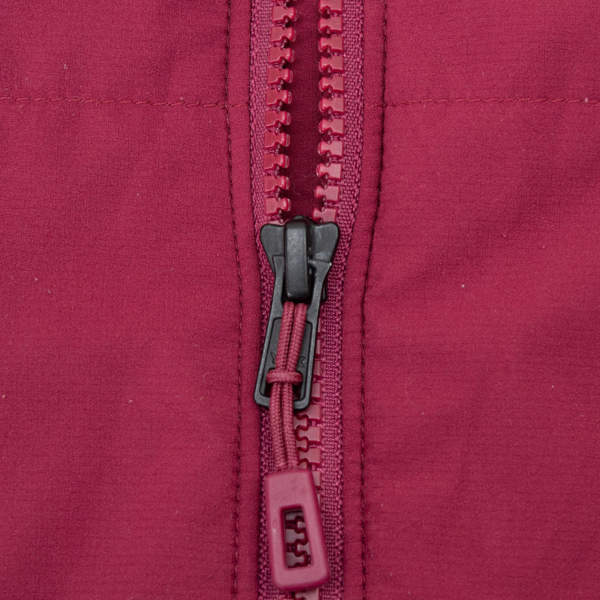 Close-up of front zipper and pull on burgundy Patagonia Zemer bomber jacket