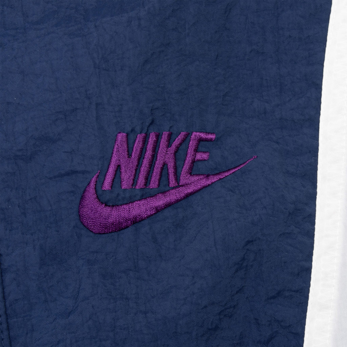 Purple embroidered Nike Swoosh chest logo on blue fabric
